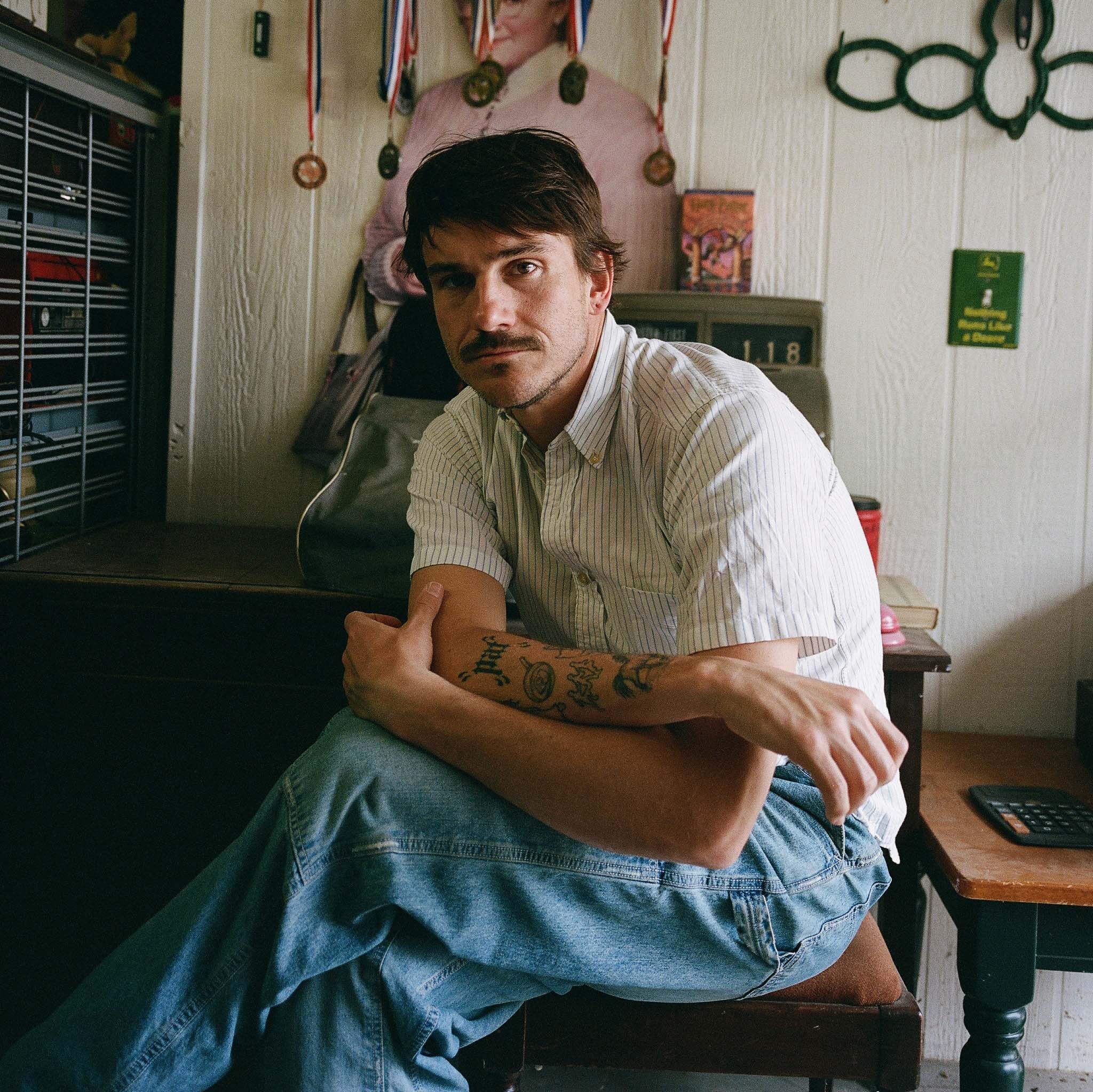 Medium Build seated in a room with records and music memorabilia